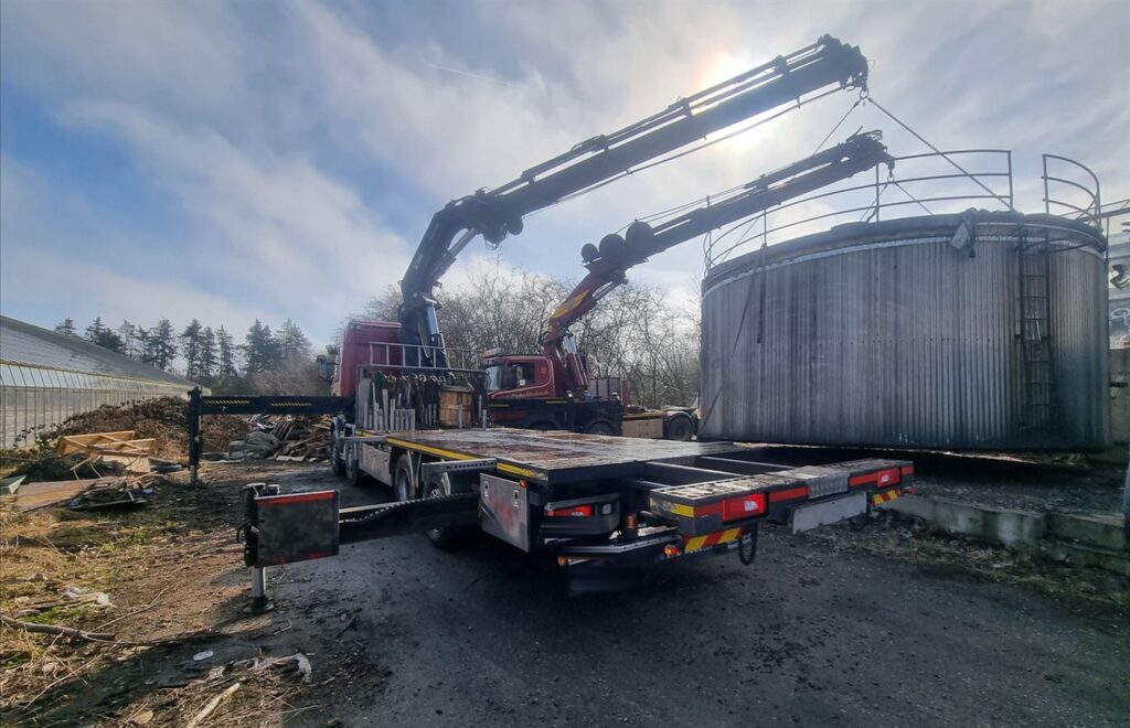 Kranbil lyfter vid en industritank