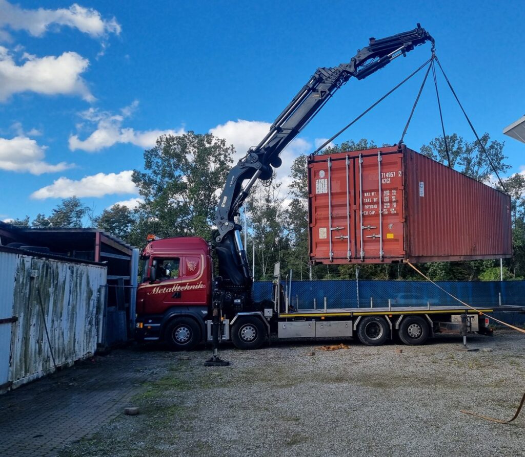 Kranbil lyfter en sjöcontainer på plats