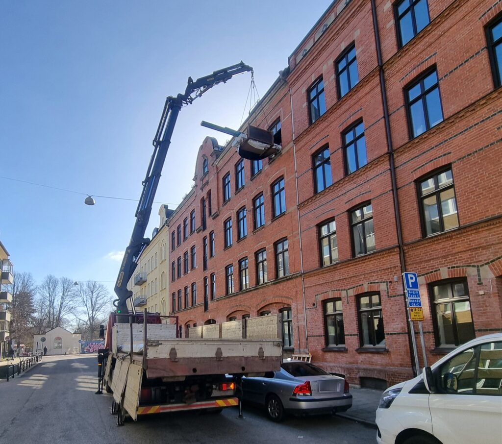 Kranbil arbetar i en smal stadsgata