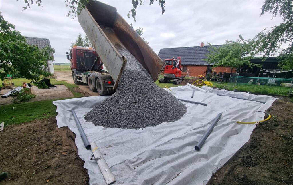 Tippbil tömmer makadam på markduk